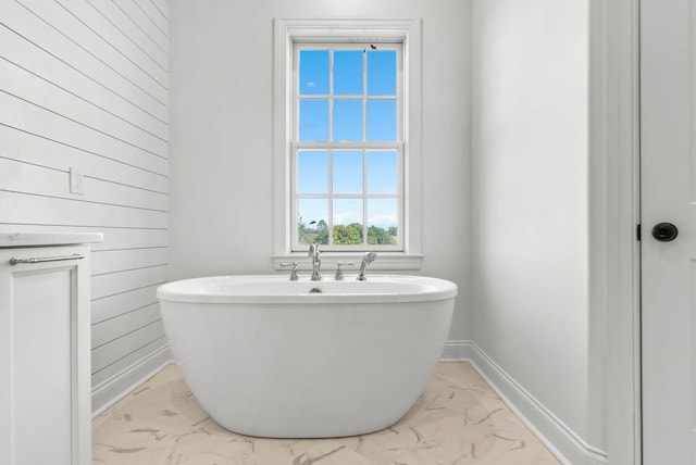 bathroom featuring a bath and wooden walls