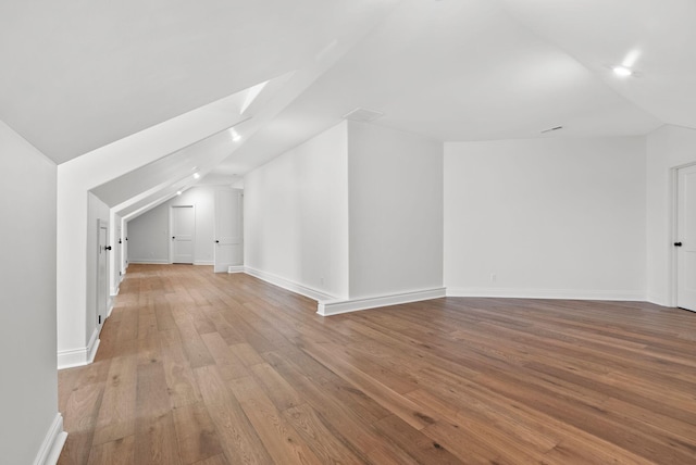 bonus room with vaulted ceiling with skylight and light hardwood / wood-style flooring