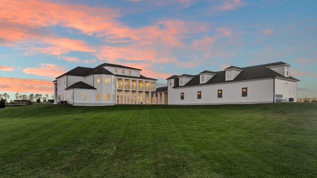 back house at dusk with a yard and a sunroom