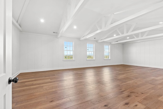 empty room with vaulted ceiling with beams, a wealth of natural light, and hardwood / wood-style floors