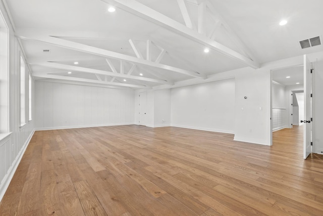 spare room featuring vaulted ceiling with beams and light hardwood / wood-style floors