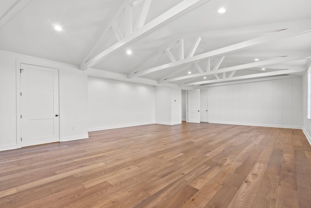 empty room featuring vaulted ceiling with beams and light wood-type flooring