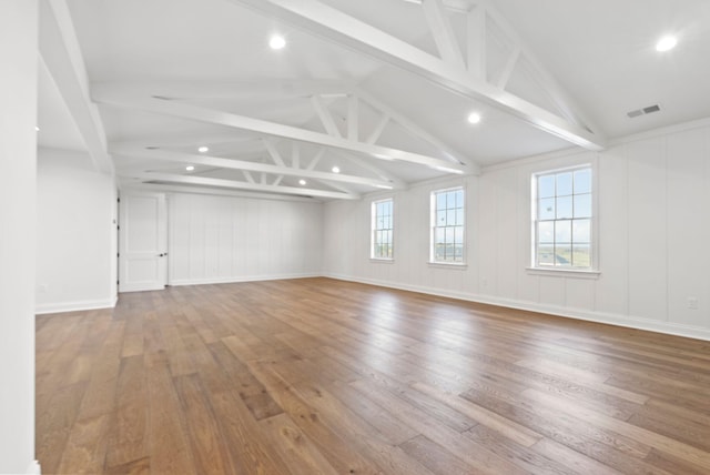 unfurnished room featuring wood-type flooring and lofted ceiling with beams