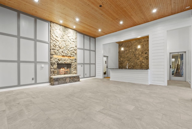 unfurnished living room with bar area, a fireplace, a high ceiling, and wooden ceiling