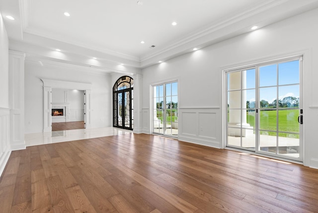 unfurnished living room featuring hardwood / wood-style flooring and ornamental molding