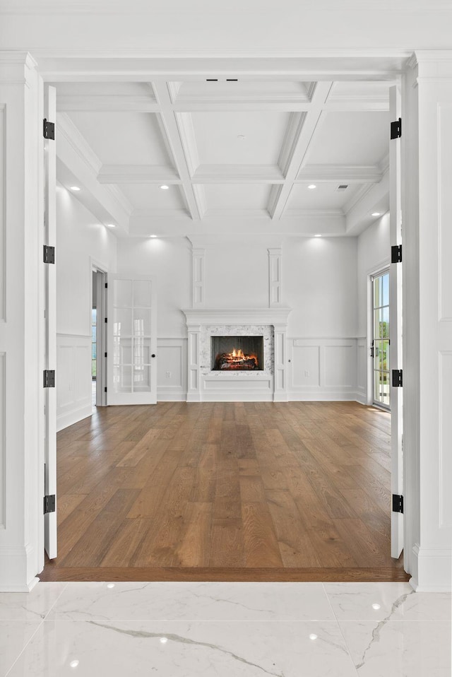 unfurnished living room featuring beamed ceiling, coffered ceiling, and a high end fireplace