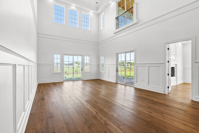 unfurnished living room with crown molding, a towering ceiling, and dark wood-type flooring