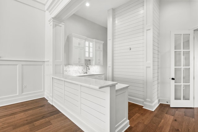 interior space with sink, light stone countertops, white cabinets, dark hardwood / wood-style flooring, and decorative backsplash