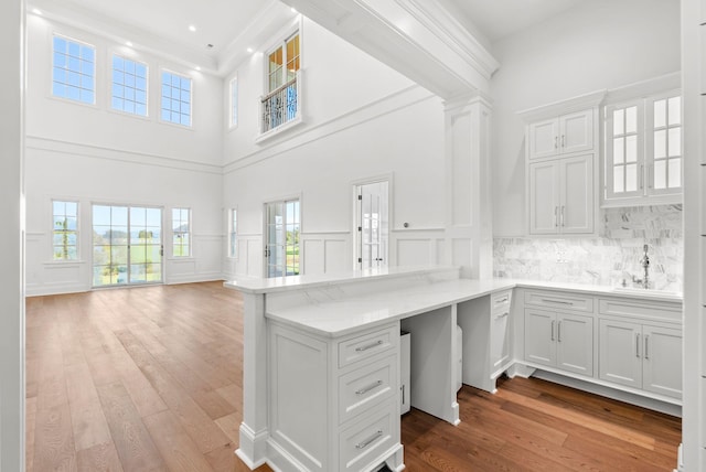 unfurnished office featuring a high ceiling, sink, and light hardwood / wood-style floors