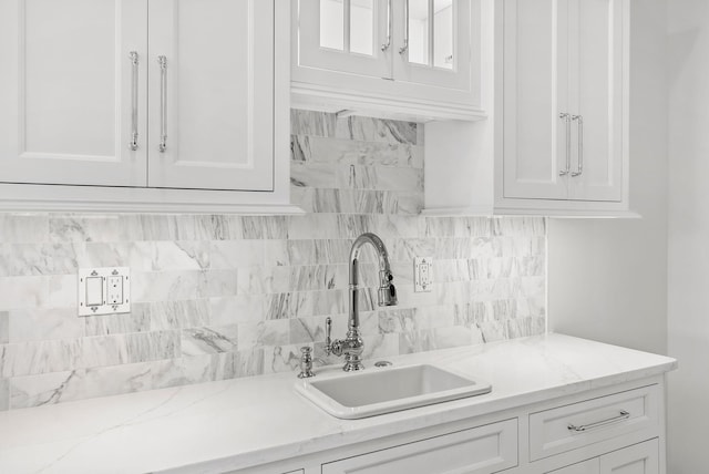 kitchen featuring white cabinetry, sink, and tasteful backsplash