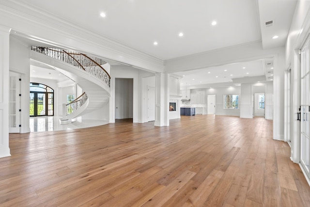 unfurnished living room featuring crown molding, french doors, and light wood-type flooring