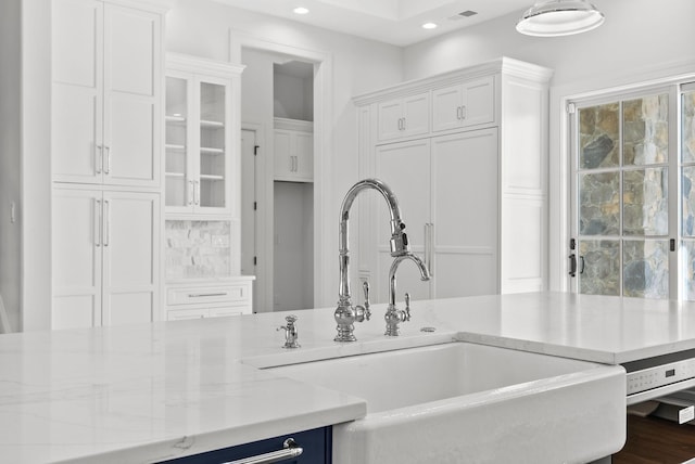 kitchen featuring a healthy amount of sunlight, sink, white cabinets, and light stone counters