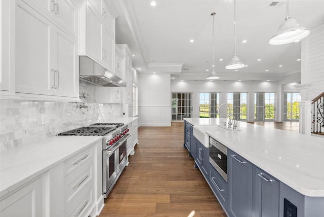 kitchen featuring pendant lighting, blue cabinetry, appliances with stainless steel finishes, white cabinetry, and a large island with sink