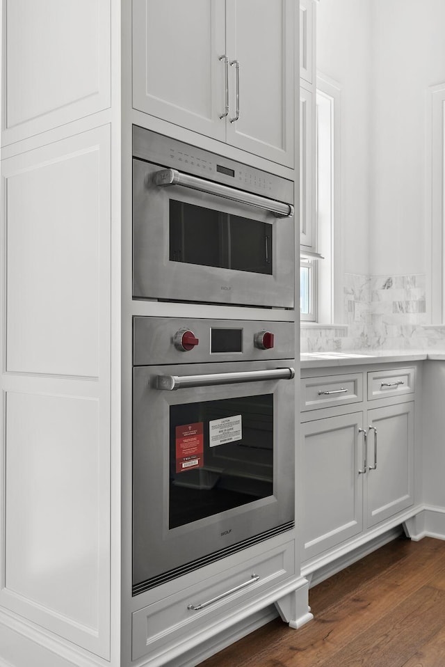 kitchen with white cabinetry, dark hardwood / wood-style floors, and double oven