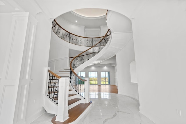 stairs featuring crown molding and a high ceiling