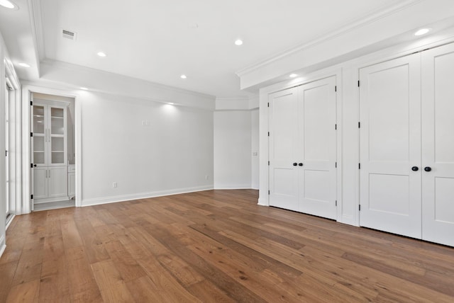 unfurnished bedroom with multiple closets, ornamental molding, and wood-type flooring