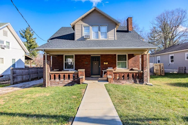 bungalow with a porch, cooling unit, and a front lawn