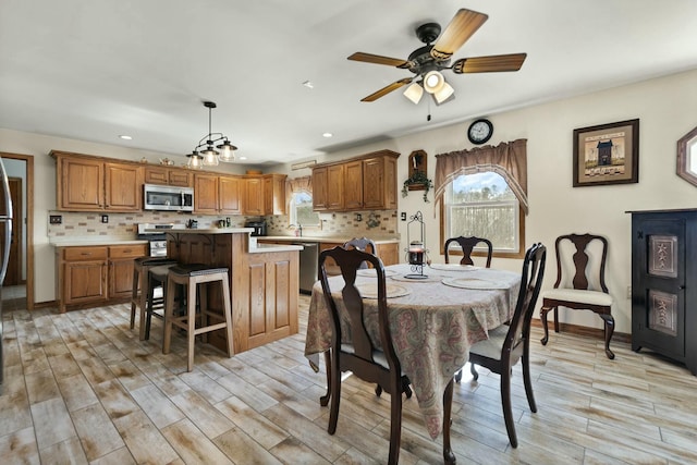 dining area with sink, ceiling fan, and light wood-type flooring