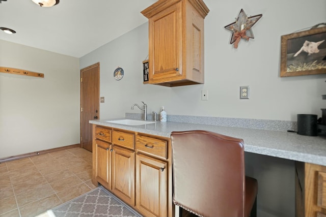 kitchen featuring light tile patterned flooring, built in desk, and sink