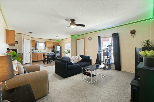 living room featuring ceiling fan, light carpet, and a textured ceiling