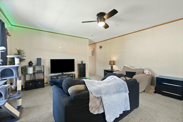 carpeted living room with crown molding and ceiling fan