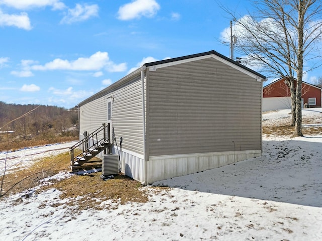 snow covered property featuring central AC unit