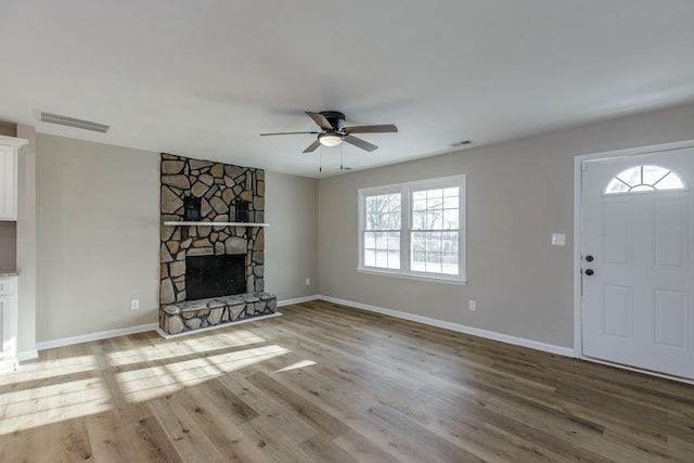 unfurnished living room with a stone fireplace, plenty of natural light, and light hardwood / wood-style floors