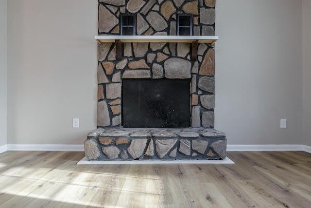 details featuring hardwood / wood-style flooring and a stone fireplace