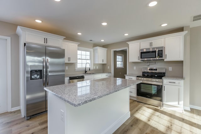 kitchen with appliances with stainless steel finishes, sink, white cabinets, and light stone counters