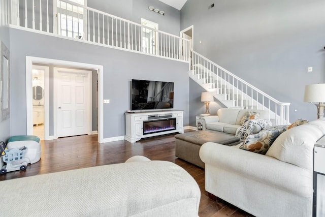 living room featuring a towering ceiling and dark hardwood / wood-style floors