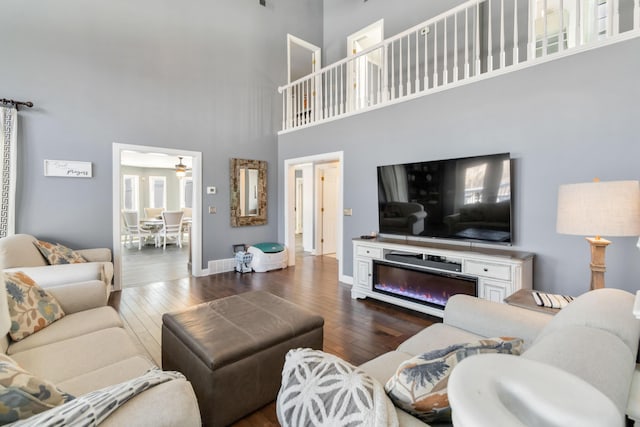 living room with a towering ceiling and dark hardwood / wood-style floors