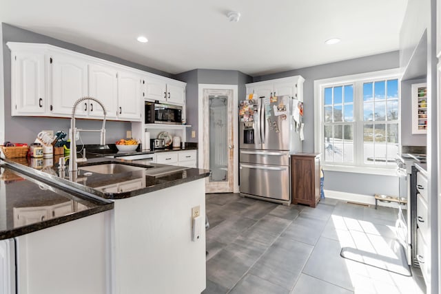 kitchen featuring stainless steel refrigerator with ice dispenser, built in microwave, sink, white cabinetry, and dark stone counters