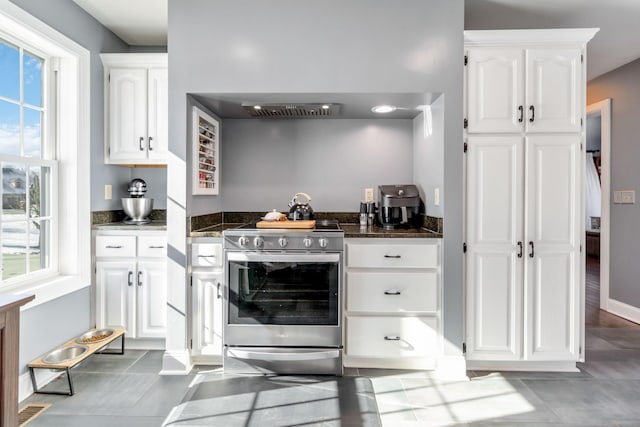 kitchen featuring white cabinetry, stainless steel electric range oven, custom range hood, and dark stone counters