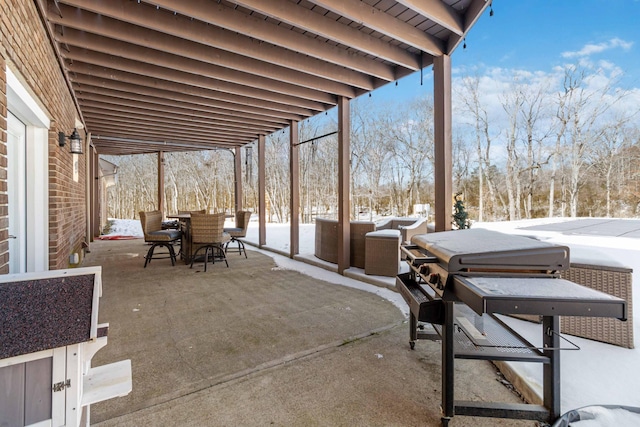 snow covered patio with area for grilling and a covered hot tub