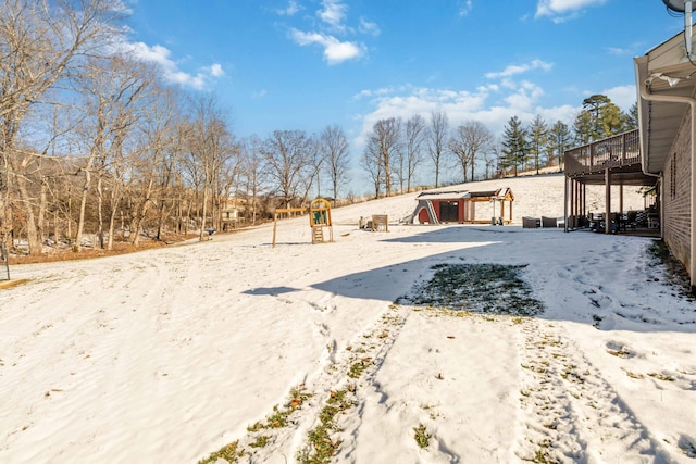 yard covered in snow with a playground and a deck