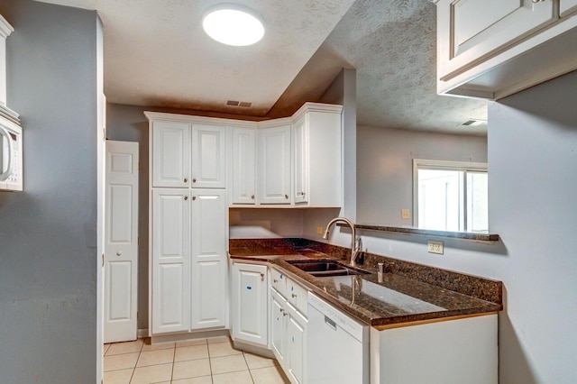 kitchen with light tile patterned flooring, white cabinetry, dishwasher, sink, and a textured ceiling