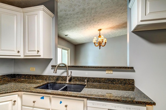 kitchen with dark stone counters, white dishwasher, sink, and white cabinets