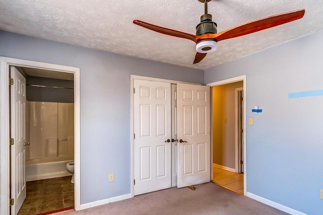 unfurnished bedroom featuring ceiling fan, connected bathroom, a textured ceiling, light carpet, and a closet