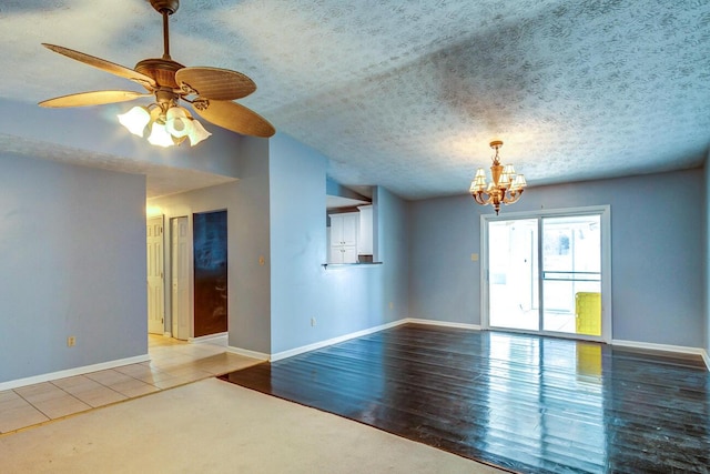 spare room featuring lofted ceiling, ceiling fan with notable chandelier, light hardwood / wood-style flooring, and a textured ceiling