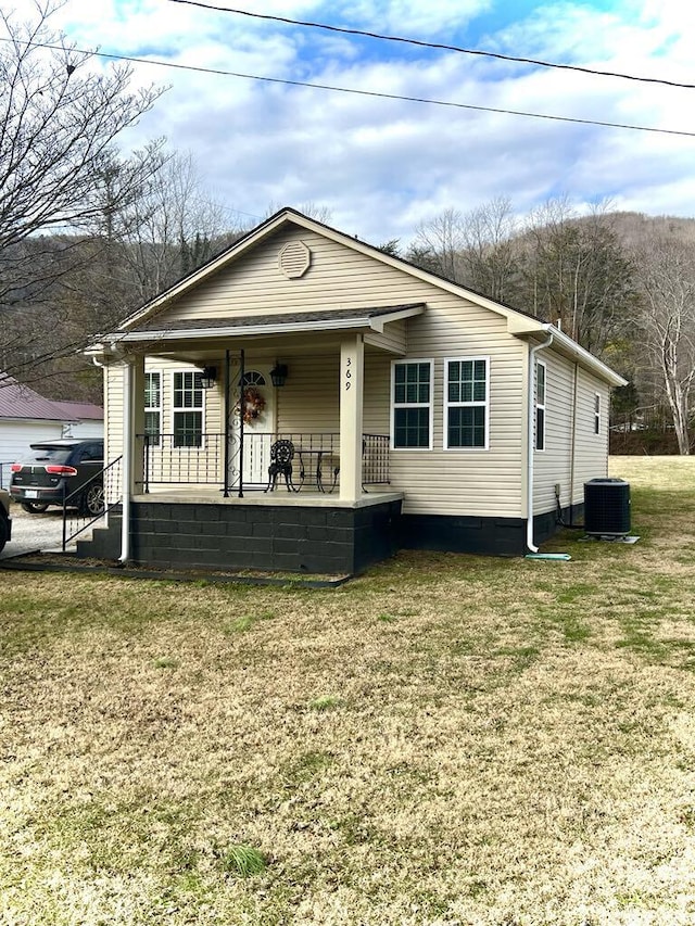 view of front of house with a front lawn, central air condition unit, and covered porch