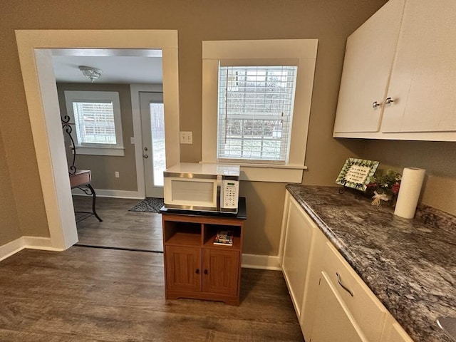 kitchen with white cabinetry, dark hardwood / wood-style floors, and dark stone counters