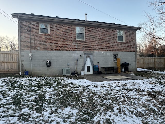 snow covered back of property featuring central air condition unit