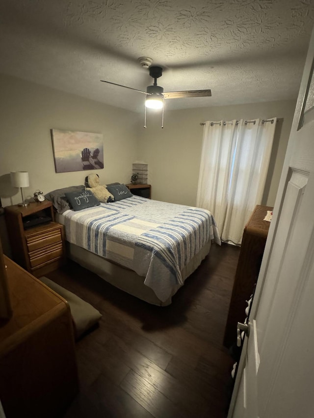 bedroom featuring dark hardwood / wood-style floors, a textured ceiling, and ceiling fan