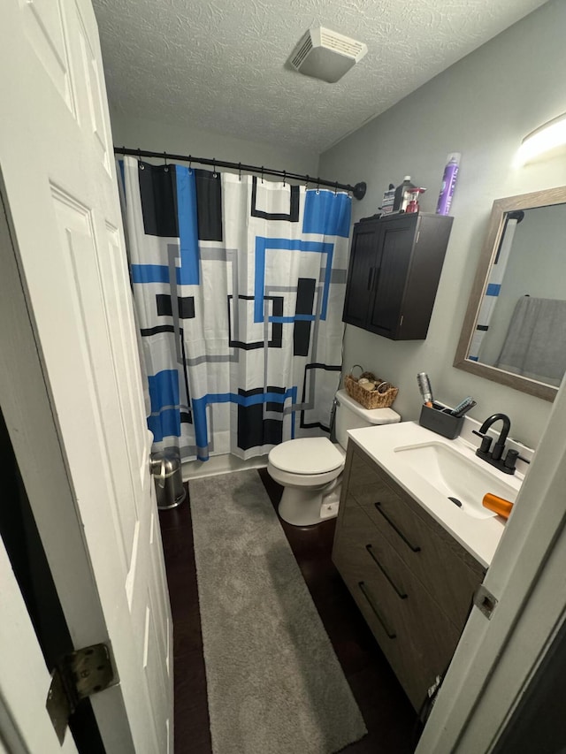 bathroom featuring vanity, toilet, a textured ceiling, and a shower with shower curtain