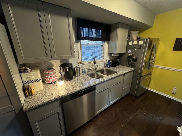 kitchen featuring dark wood-type flooring, sink, appliances with stainless steel finishes, gray cabinets, and light stone countertops