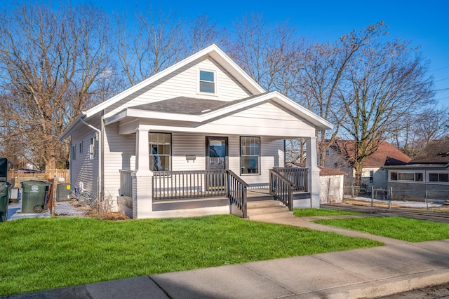 bungalow with cooling unit, a front lawn, and covered porch