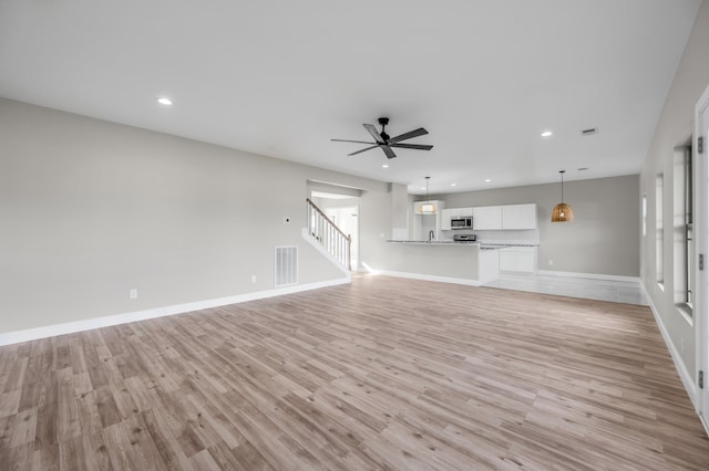 unfurnished living room featuring ceiling fan and light hardwood / wood-style floors