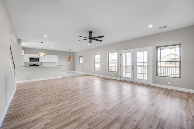 unfurnished living room featuring ceiling fan, sink, light hardwood / wood-style floors, and french doors