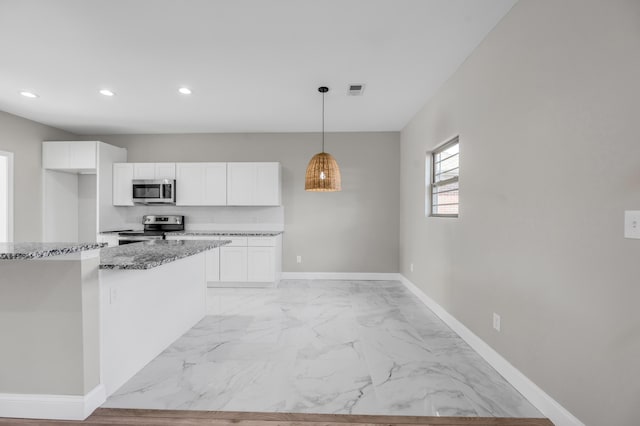 kitchen with dark stone countertops, stainless steel appliances, decorative light fixtures, and white cabinets