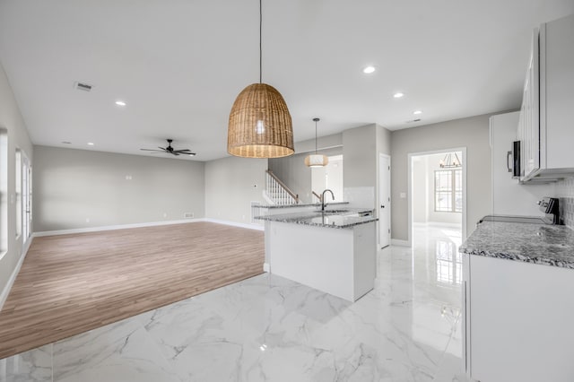 kitchen with ceiling fan, stove, white cabinets, stone countertops, and decorative light fixtures